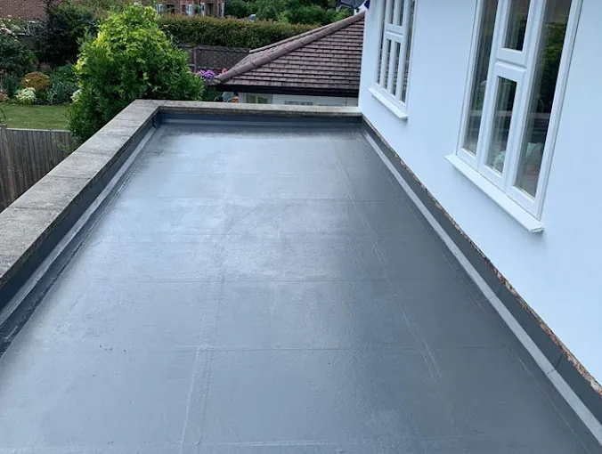 Seamless grey flat roof with neat upstand trims against the house wall