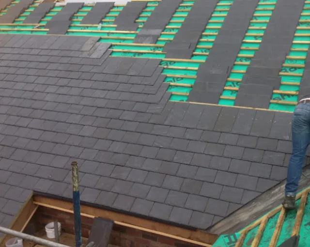 New slates being laid over breathable membrane and battens during a re-roof