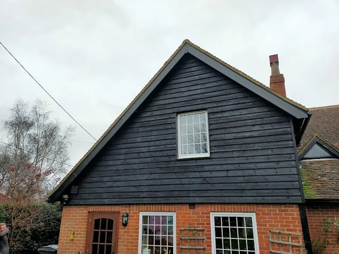 Dark timber weatherboard cladding on a gable end with white fascias